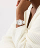 Person wearing a white robe with a watch on a light background