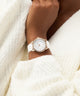 White watch on a wrist with a white textured background