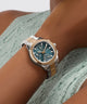 Close-up of a person wearing a GUESS watch on a light background