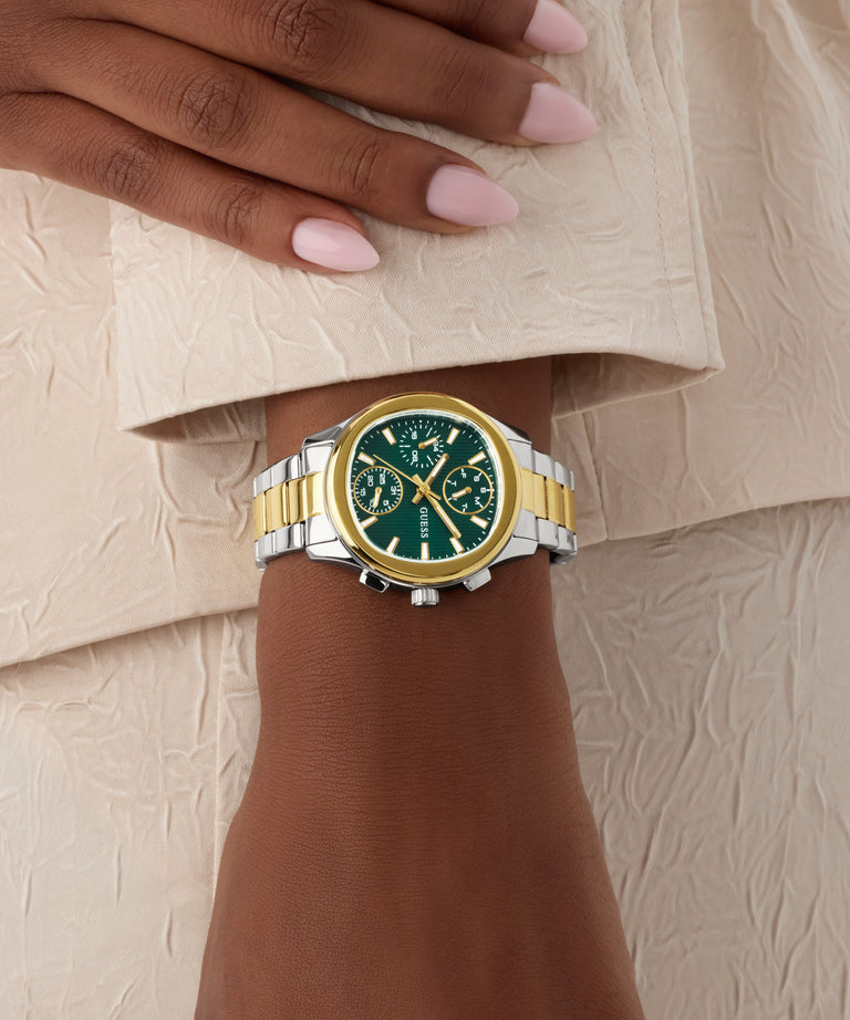 Gold and silver GUESS Ladies Birdie 2-Tone Analog Watch on a wrist with a neutral background