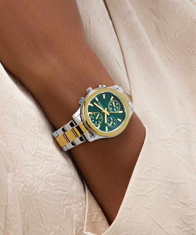 Gold and silver GUESS Ladies Birdie 2-Tone Analog Watch on a wrist with a neutral background