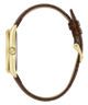 A close-up side view of a watch with a gold-tone case and a brown leather strap featuring a subtle textured pattern, set against a plain white background.