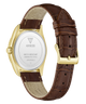 The back view of a GUESS wristwatch with a brown leather strap, gold-tone case, and white back cover showing the brand name and specifications.
