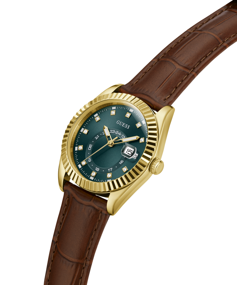 A GUESS wristwatch with a gold-tone fluted bezel, dark blue-green dial, and a brown leather strap, shown on a plain white background. lifestyle