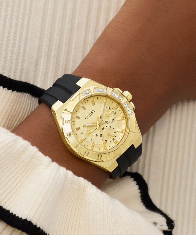 Gold GUESS Ladies White Gold Tone Analog Watch with black strap on a wrist against a neutral background