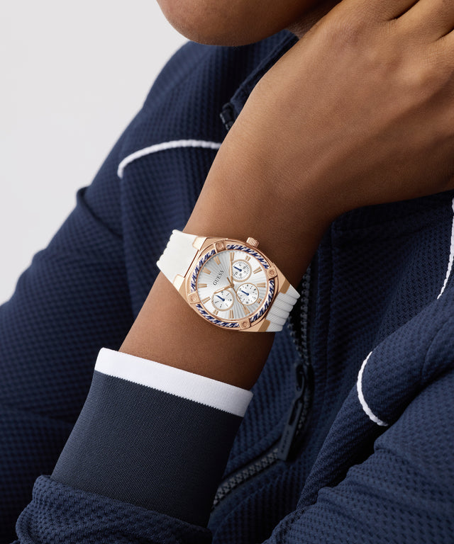 Person wearing a rose gold GUESS Ladies White Rose Gold Tone Analog Watch with a white strap on a plain background