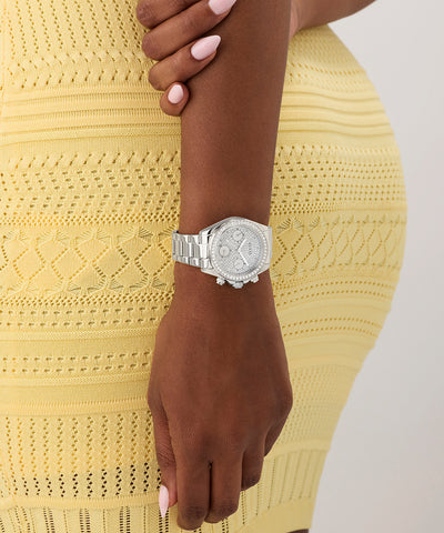 GUESS Ladies Victoria Silver Tone Analog Watch on a wrist with a yellow textured dress