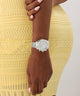 GUESS Ladies Victoria Silver Tone Analog Watch on a wrist with a yellow textured dress