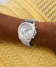 GUESS Ladies Victoria Silver Tone Analog Watch with gemstones on a wrist against a yellow lace background