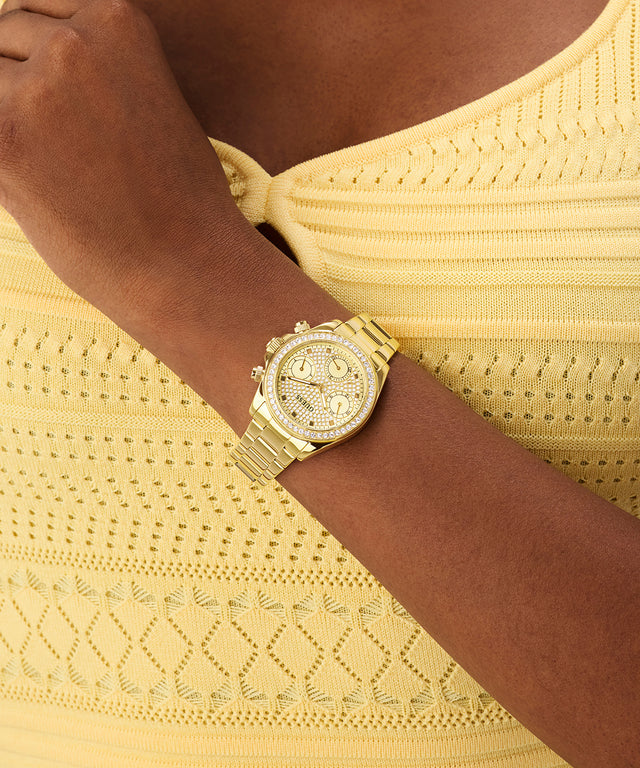 GUESS Ladies Victoria Gold Tone Multi-Function Watch on a wrist with a yellow top
