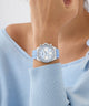 GUESS Ladies Ice Blue Silver Tone Analog Watch with Swarovski ReCreated™ crystals with blue strap on wrist against a light blue background