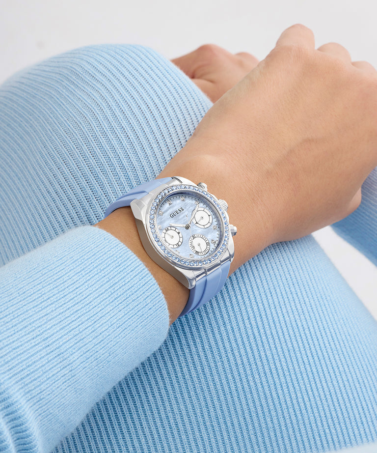 Silver GUESS Ladies Ice Blue Silver Tone Analog Watch with Swarovski ReCreated™ crystals with gemstones on a wrist wearing a light blue sweater