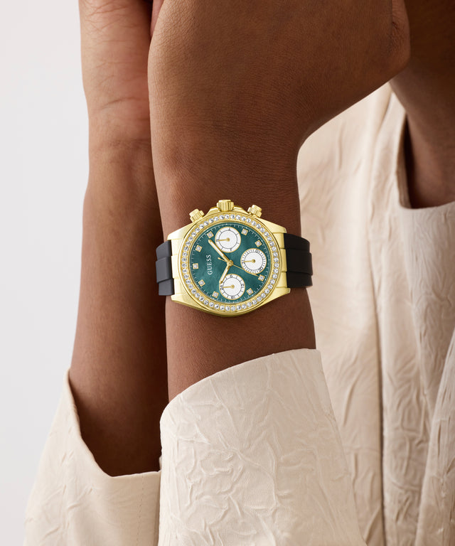 Luxury watch with green face and gold casing on a wrist, against a neutral background