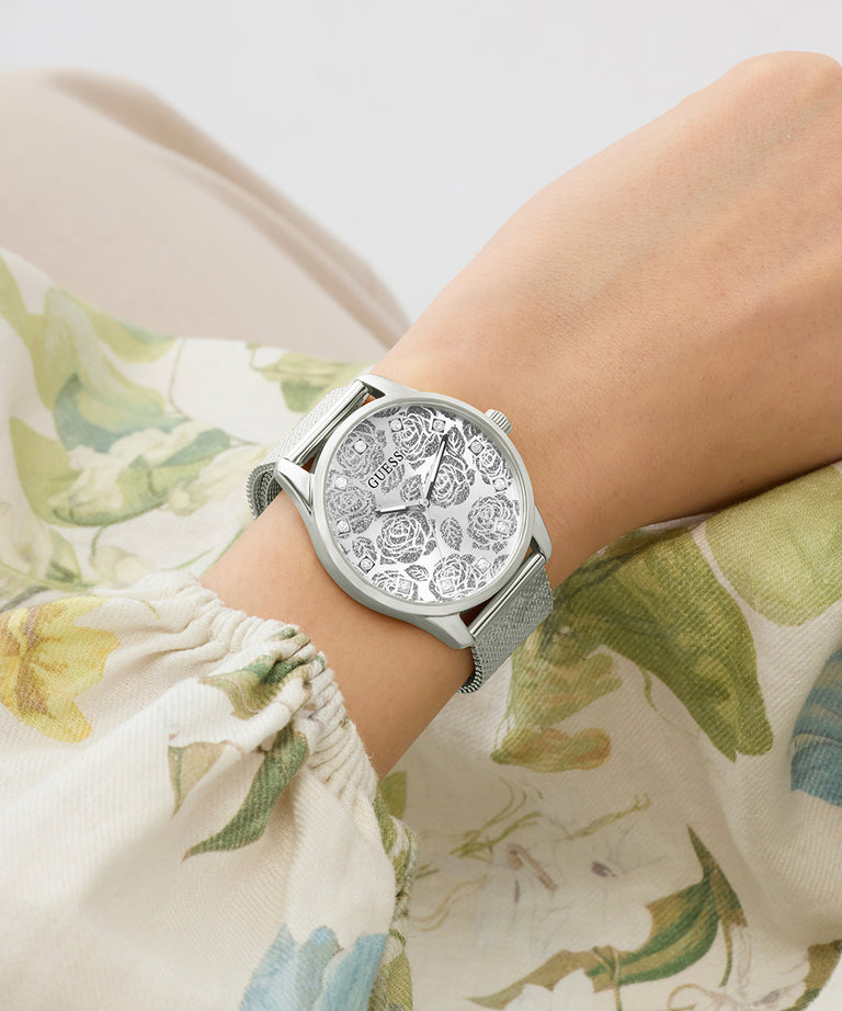 Silver watch on a wrist with floral-patterned fabric background