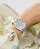 Silver watch on a wrist with floral-patterned fabric background