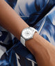 GUESS Ladies White Silver Tone Analog Watch on a wrist with a blue floral patterned fabric background