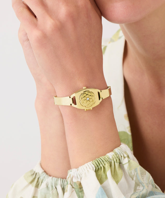 Gold GUESS Ladies Gold Tone Analog Watch on a wrist with a light background