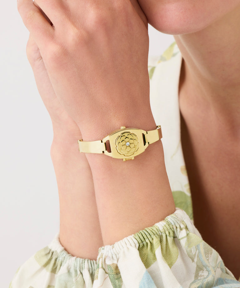 Gold GUESS Ladies Gold Tone Analog Watch on a wrist with a light background