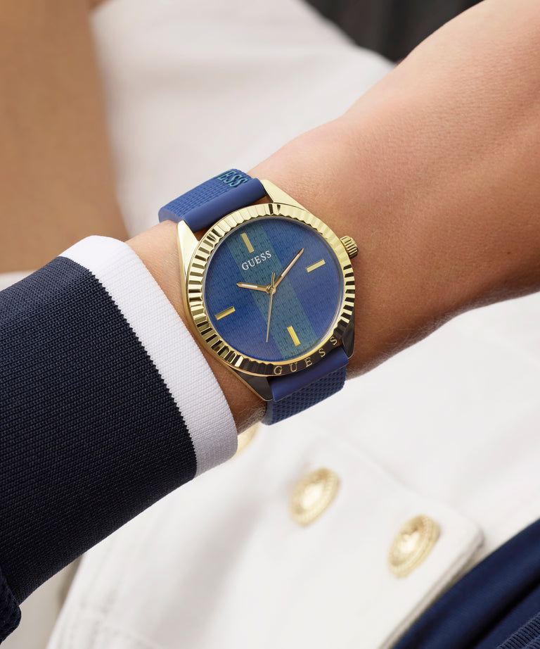 Blue and gold GUESS Ladies Blue Gold Tone Analog Watch on a wrist with a white and navy outfit