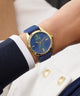 Blue and gold GUESS Ladies Blue Gold Tone Analog Watch on a wrist with a white and navy outfit