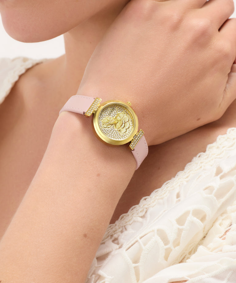 GUESS Ladies Light Pink Gold Tone Analog Watch watch with pink strap worn by a person in a white lace garment