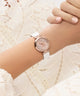 Rose gold GUESS Ladies White Rose Gold Tone Analog Watch on a wrist with a white lace background