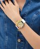Gold GUESS Ladies Pride Limited Edition White Gold Tone Analog Watch with colorful accents on a wrist against a denim background
