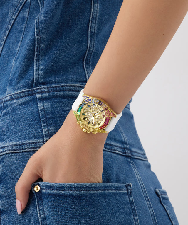Gold GUESS Ladies Pride Limited Edition White Gold Tone Analog Watch with a white strap on a person's wrist, wearing blue jeans.