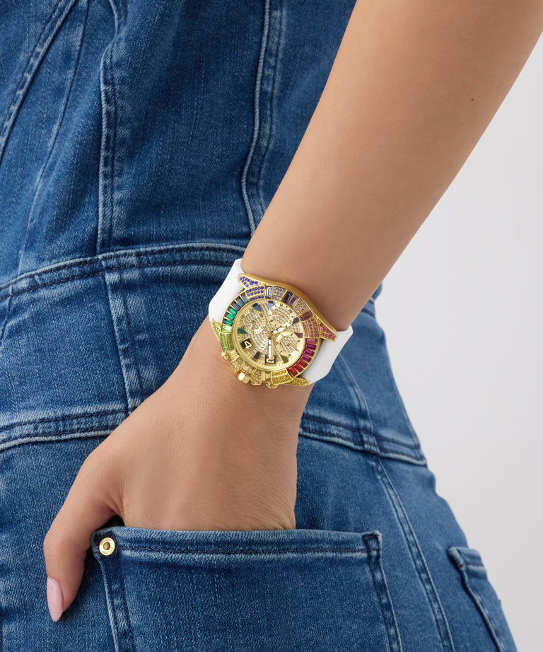 Gold GUESS Ladies Pride Limited Edition White Gold Tone Analog Watch with a white strap on a person's wrist, wearing blue jeans.