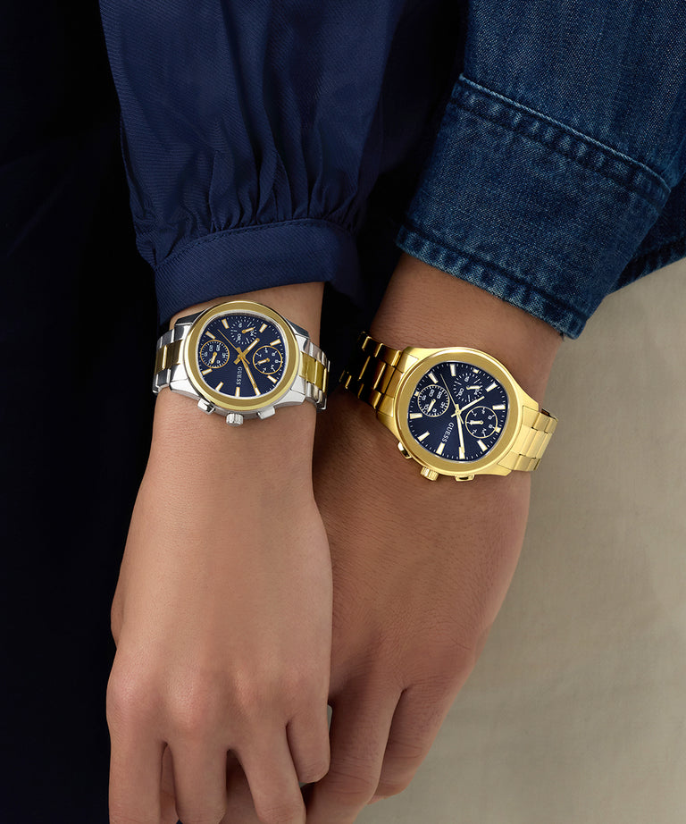 Two wrists wearing gold watches with blue faces against a dark background