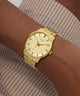 Gold watch on a wrist with a striped shirt background