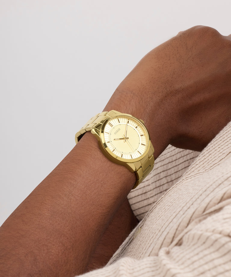 Gold watch on a wrist with a neutral background