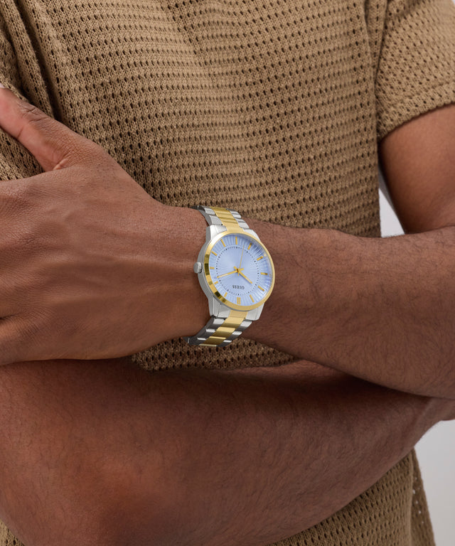 Gold watch on a wrist with a brown textured shirt