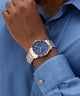 Gold and silver watch on a wrist with a blue shirt background