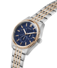 Two-tone watch with blue dial and gold accents on a white background lifestyle