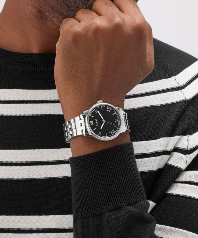 Person wearing a black and silver GUESS Mens Silver Tone Analog Watch on a black and white striped sweater.