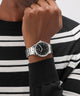 Person wearing a black and silver GUESS Mens Silver Tone Analog Watch on a black and white striped sweater.