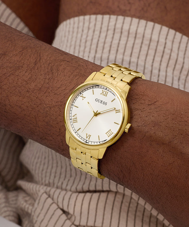 Gold watch on a wrist with a neutral background