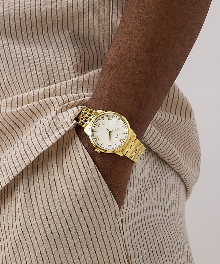 Gold watch on a wrist with a neutral background