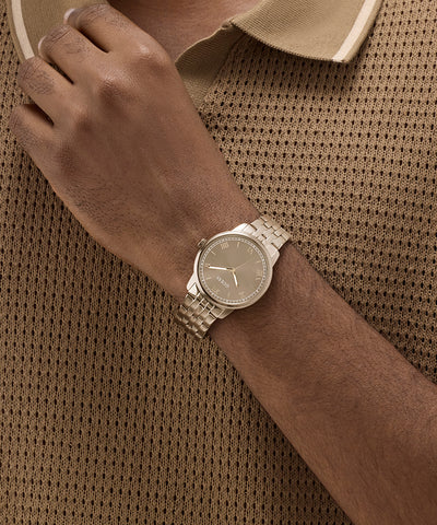 GUESS Mens Coffee Analog Watch on a wrist against a brown textured background
