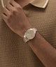 GUESS Mens Coffee Analog Watch on a wrist against a brown textured background