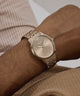 Gold GUESS Mens Coffee Analog Watch on a wrist with a neutral background