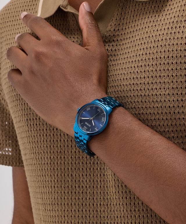 Person wearing a blue watch on a brown textured shirt