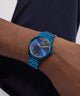 Person wearing a blue Guess watch on a plain background