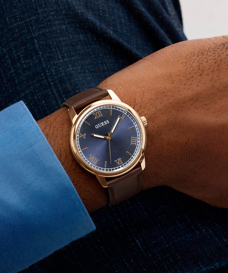 Close-up of a person wearing a Guess watch on a wrist with a blue shirt sleeve.
