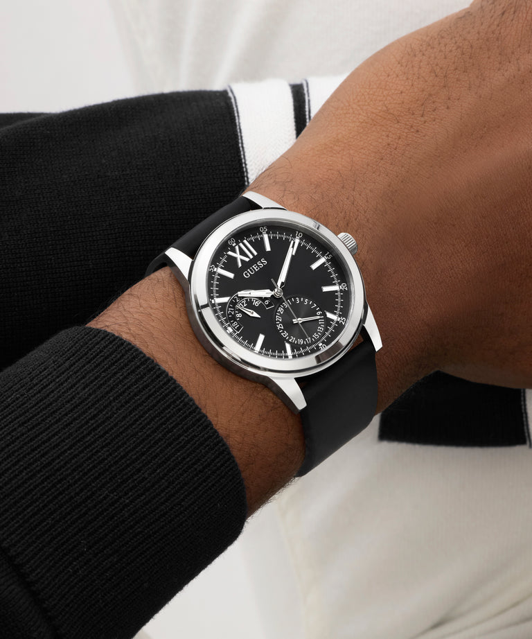 Close-up of a person wearing a GUESS Mens Black Silver Tone Analog Watch watch on a white background