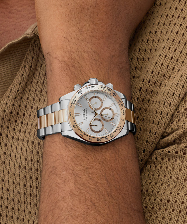 Silver and gold GUESS Mens Arthur 2-Tone Analog Watch on a wrist with a textured brown background