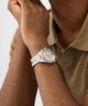 Close-up of a wrist wearing a silver and gold GUESS Mens Arthur 2-Tone Analog Watch with a neutral background