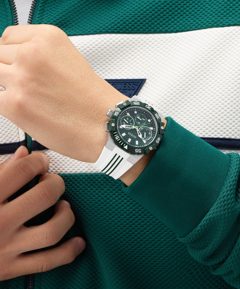 Person wearing a green sports GUESS Mens White Silver Tone Analog Watch on a green and white striped background