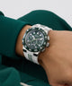 Person wearing a Guess watch on a wrist with a green sleeve.